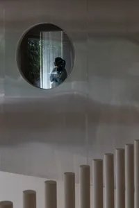 A metallic surface with a circular reflection of a person in a window.