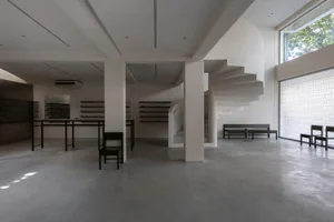 A minimalist, modern retail shop with concrete flooring and minimalist furniture and shelving.