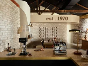 Industrial-style coffee shop featuring brick walls, metal accents, and wood furniture.