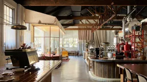 A spacious, industrial-style coffee shop with wooden materials and a large barista counter.