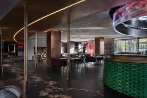 Contemporary restaurant bar interior with metallic columns, concrete walls, and brick seating.