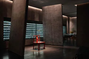 A minimalist restaurant bar with metal furniture and glass walls.