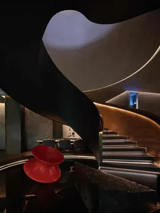 A modern restaurant interior with a spiral staircase featuring metallic and glass materials.