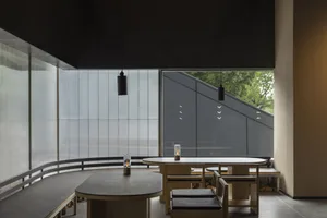 A modern restaurant interior with wooden tables and concrete flooring.