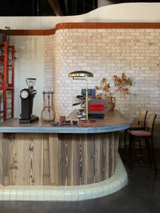 A cozy coffee shop with wooden, concrete, and brick interior elements, featuring coffee-making equipment and seating arrangem