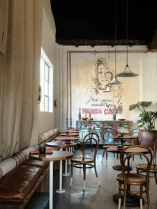 Interior of a cafe with wooden tables, fabric seating, and glass displays.