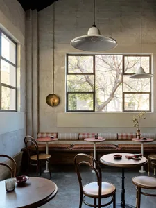 A cafe interior with wooden tables, metal chairs, and glass pendant lights.