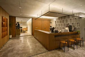 A coffee shop with a wooden counter and a concrete floor, featuring coffee-making equipment and seating.