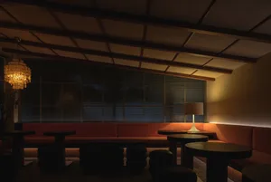 A cozy cafe interior with fabric seating, a concrete column, wooden lampshades, and a warm ambiance.