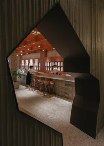 A retail storefront with an industrial design featuring a concrete wall and wooden elements.