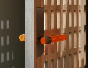 An orange acrylic door handle attached to a wooden grid door.