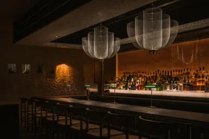 Modern bar interior with concrete counter and metallic lighting fixtures.