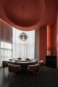 A modern dining room with a metallic table centerpiece, wooden chairs, and sheer textiles for soft lighting.