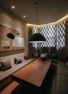A modern interior design featuring soft fabric textures with a large abstract painting and a hanging lamp in the foreground.