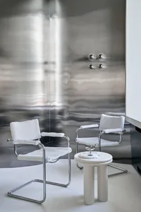 Minimalist modern interior design featuring a sleek glass table and chairs against a metallic wall.