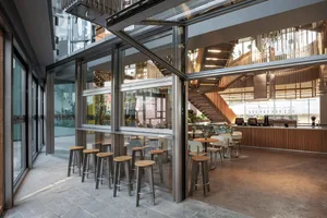 A modern minimalist cafe interior with glass, metal, and concrete elements