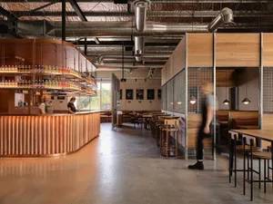 Industrial restaurant interior featuring a copper bar with wooden seating and exposed ductwork.