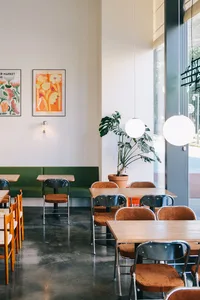 Cafe interior with wooden tables, concrete flooring, and potted plants.