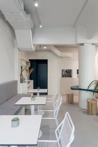 Minimalist cafe interior with white furniture and open space.