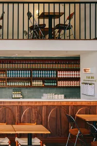 An image showcasing a cafe interior with wooden shelving filled with canned drinks and bottles arranged in an elegant display