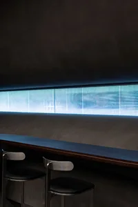 Industrial-style bar counter with metal stools and a dark, minimal backdrop.