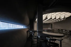 Industrial-style restaurant interior featuring metal stools and concrete walls and floor