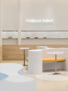 Modern minimalist coffee shop interior with white concrete elements and a yellow seating area.