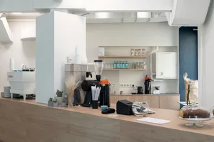 現代咖啡店室內空間，設有木質吧台、飲料分裝器及各式咖啡製作設備。