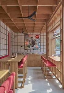 Modern restaurant interior with wooden furniture and vibrant artwork.