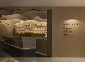 Modern bar with concrete shelves displaying various bottles of alcohol.