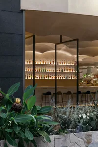 現代酒吧室內展示玻璃吧台，陳列大量各式酒類飲品。