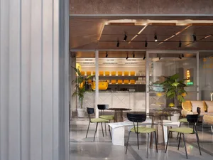 A modern coffee shop interior with contemporary furniture and green accents.