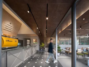 A modern coffee shop with concrete walls and glass partitions, featuring contemporary interior design elements.