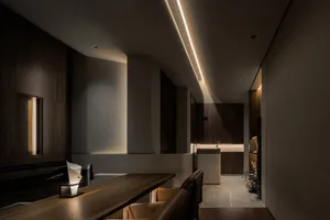 Modern minimalist dining room with wooden furniture and recessed lighting.