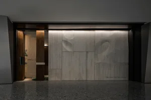 Modern entrance to a restaurant featuring marble walls and a wooden door.