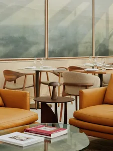 Modern restaurant lounge with contemporary furniture, leather upholstered seats, wooden tables, and glass accents.
