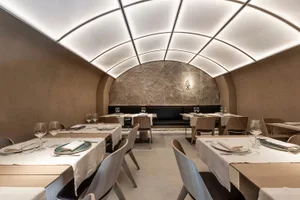 A modern restaurant interior with marble walls, wooden tables, and metal accents