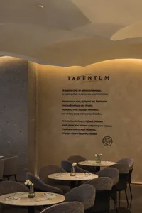 A cozy restaurant interior with textured walls and round tables set with white tableware.