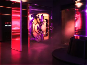 A large, illuminated metal door in a darkened bank lobby.