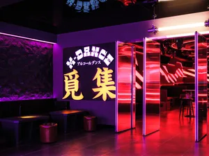 Industrial-style nightclub interior with metallic glass panels and neon lighting.