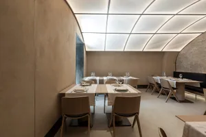 A minimalist restaurant with wooden tables and concrete walls