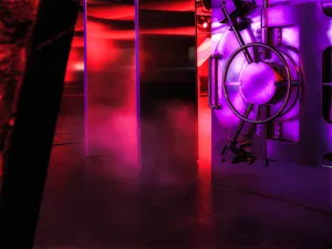 A modern bank vault illuminated with purple lighting and featuring metallic materials.