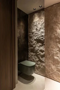 Modern bathroom with stone walls and a minimalist toilet.