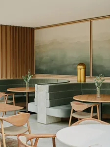 A modern cafe with green velvet seating and marble accents.