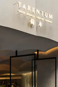Modern restaurant entryway featuring a concrete wall and heavy glass doors