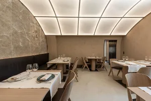 Modern restaurant interior with minimalist design featuring neutral-toned decor and lighting.