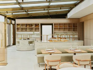 Modern restaurant interior with marble countertops, concrete bar, brass accents, and mirrors