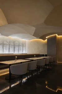 Modern restaurant interior featuring marble and concrete materials, designed to create a sophisticated atmosphere.