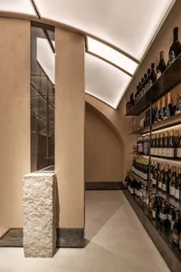 Modern wine tasting room with concrete walls, glass shelves, and metallic accents.