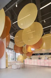 A cozy coffee shop interior features metallic perforated disks hanging from the ceiling.